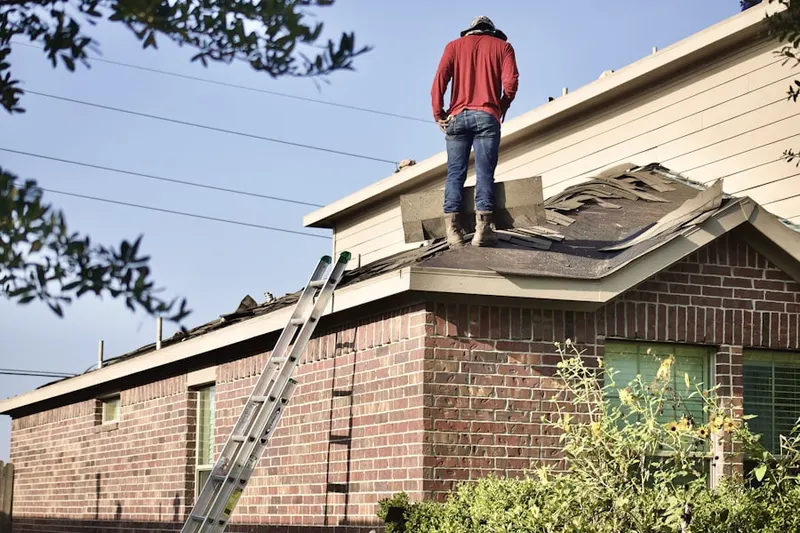 Professional roofer working on a residential roof in Andrews Manor